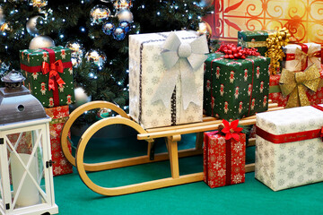 next to the Christmas tree are packed gifts and a wooden sled. christmas holidays