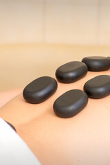 Fototapeta na wymiar Hot stone massage therapy. Caucasian young man getting a hot stone massage on back at spa salon