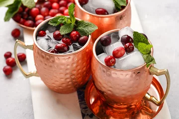Küchenrückwand glas motiv Traditional american alcoholic beverage moscow mule in copper mugs with cranberry and mint on white marble board - non-alcoholic cocktail version © Romana