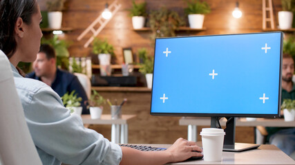 Businesswoman sitting at desk looking at mock up green screen chroma key computer with isolated display analyzing marketing project ideas. Manager woman working at company strategy in startup office