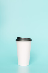 Take-out coffee with a black lid on top of the sky blue background.