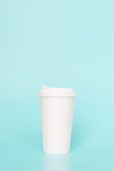 Take-out coffee with a white lid on top of the sky blue background.