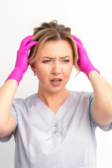 The emotionally shocked young female medical worker holding hands on her head fell into panic on white background, infection, epidemic, virus, and disease concept