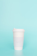 Take-out coffee with a white lid on top of the sky blue background.