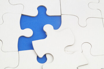 White jigsaw puzzles background, one piece missing and ready to connecting. Business strategy,  teamwork, problem solving and complete mission concept. 