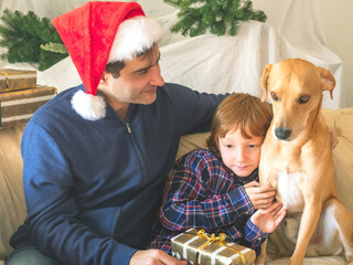 Dad and son in santa caps and dog on christmas