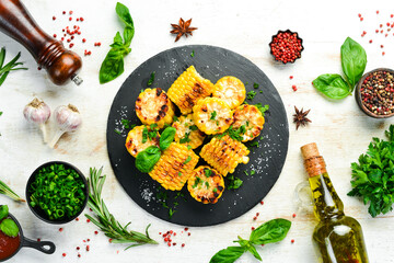 Food. Baked corn with parsley and basil on a black stone plate. Top view. Free space for your text.