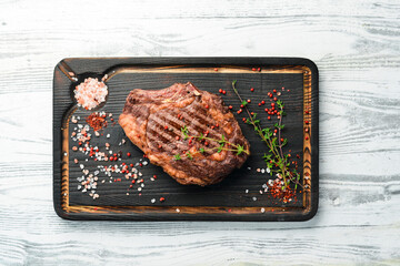 Grilled beef steaks with spices on a white wooden background. Top view, free copy space.
