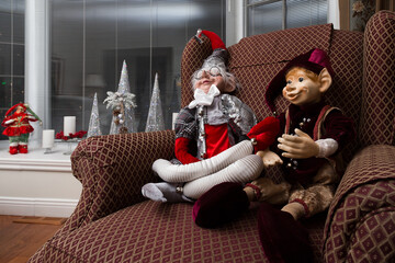 Interior of home with Christmas decorations, including two amusing large elves sitting in traditional style armchair