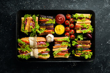 A set of homemade sandwiches with sausage, cutlet, lettuce, onions, tomatoes and vegetables. Rustic style. Free copy space.