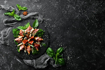 Figs with prosciutto and blue cheese and basil on a black stone plate. Food. Top view. Free space for your text.