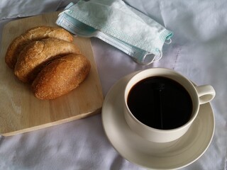cup of coffee and whole wheat bread with face mask off in New Normal Life 