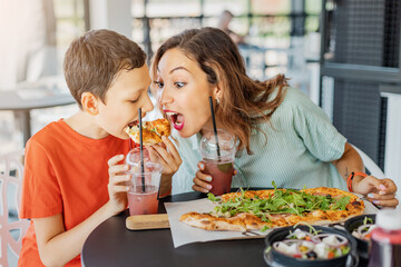 Mother and son eat delicious Italian pizza in a pizzeria or cafe. Joint leisure and fast food concept