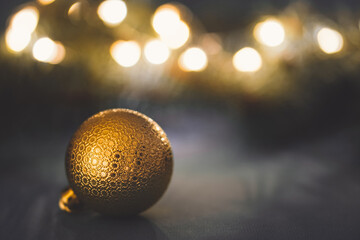 Golden christmas ball on holiday lights background. New year greeting card. Copy space for text