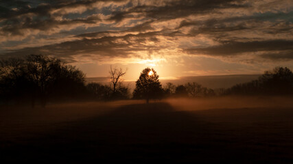 Beautiful sunrise panorama with cloudscape, sunbeams and fog