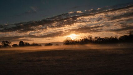 Sunbeams and fog at sunrise or sunset