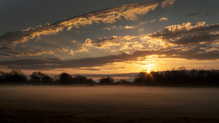 Fototapeta na wymiar Sunrise panorama with cloudscape, sunbeams and fog