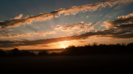 Beautiful sunrise panorama with cloudscape sunbeams and fog