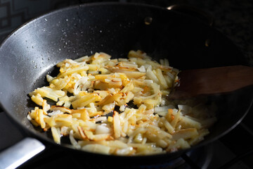 onion and friendose cut potato over vegetable oil in a black skillet