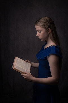 reanissance portrait of woman in blue dress reading a book in rembrandt style