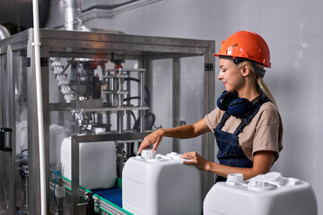 female in hardhat closes the lid of canister with pesticides, preparing plasctic canister in...