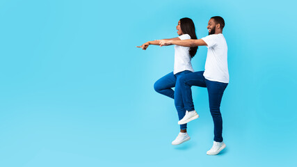 Smiling black couple pointing aside at free copy space