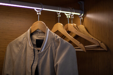 Clothes and hangers hanging in the interior illuminated wardrobe