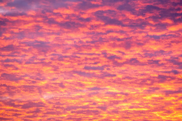 bright pink and orange puffy clouds in the sky during sunrise or sunset illuminating the sky in...