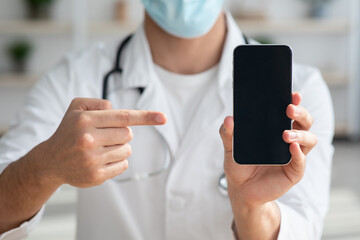 Unrecognizable doctor pointing at smartphone with empty screen, closeup