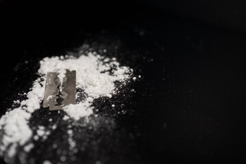 Razor Blade on drug powder on reflection black background.Copy space.