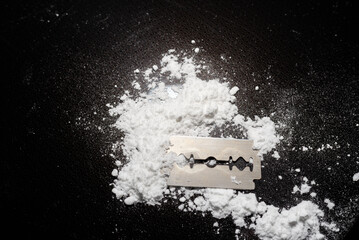 Razor Blade on drug powder on reflection black background.Copy space.