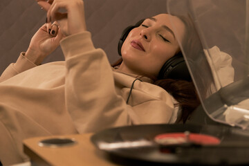 woman lying in bed smiling listening music with headphones and accompanying, happy woman listening to music with headphones while lying down