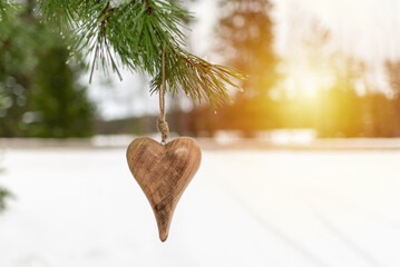 Wooden heart Pine branch in winter snow close up. Snow fir branch in forest. a symbol of romantic...