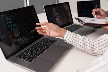 co-working concept the female wearing white vertical striped blouse reporting the subject on her computer while her partner writing it down on the paper