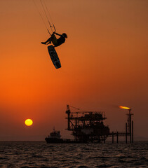 Extreme Sport Kitesurfing against Offshore Jack Up Rig in The Middle of The Sea at Sunset Time