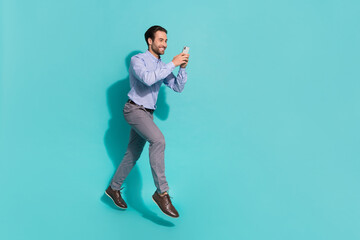 Fototapeta na wymiar Photo of social media addict man jump move read phone feedback wear violet shirt isolated turquoise color background