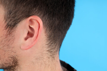 Obraz premium Young man's head on blue background, hearing problem concept