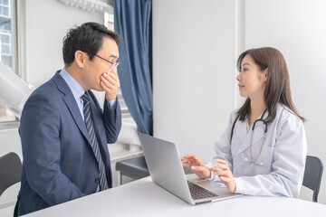 Obraz premium パソコンで診察する女医と男性患者メディカルイメージ