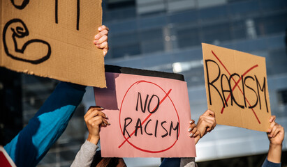 Crowd of people standing with signboards against racism on city street