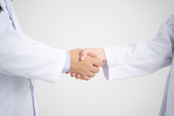 Fototapeta premium 握手をする男女の白衣を着た医療従事者・手元アップ白背景