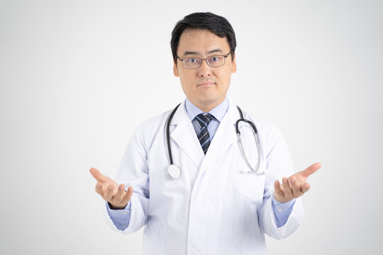 パソコン画面越しにオンライン診療で説明する男性医師イメージ・白背景