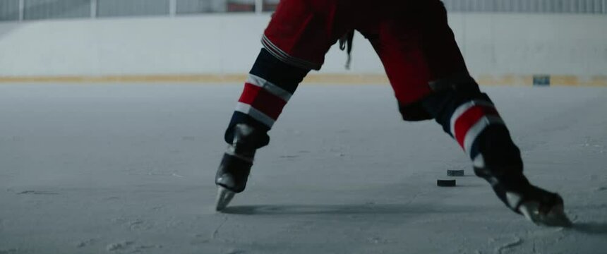 MED Professional ice hockey player practices his slap shots on the indoor rink alone. Shot with 2x anamorphic lens