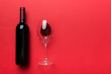 Glass of red wine and a bottle on colored table. Flat lay, top view wth copy space