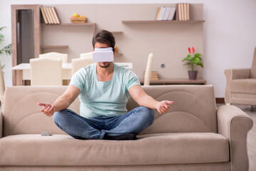 Fototapeta premium Young man student wearing virtual glasses at home