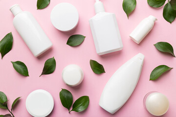 Organic cosmetic products with green leaves on color background. Flat lay