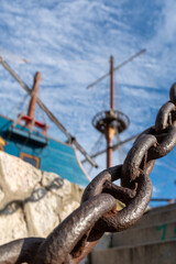 Strong chain link at the side of a dock harbour with ship in background strength connection concept