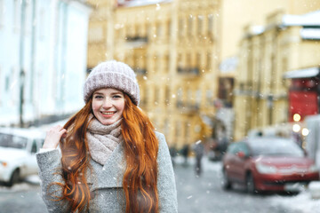 Lovely ginger lady walking at the old city with snowflakes