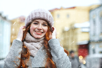 stylish ginger lady walking at the old city with snowflakes