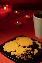 A pile of home made gingerbread cookies on a plate against festive background.
