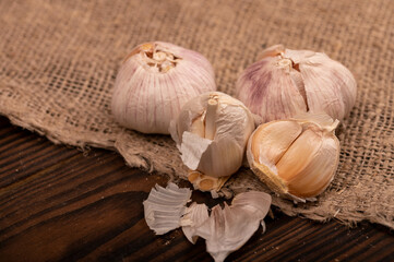 Heads of young garlic on a table covered with burlap, close-up, selective focus.